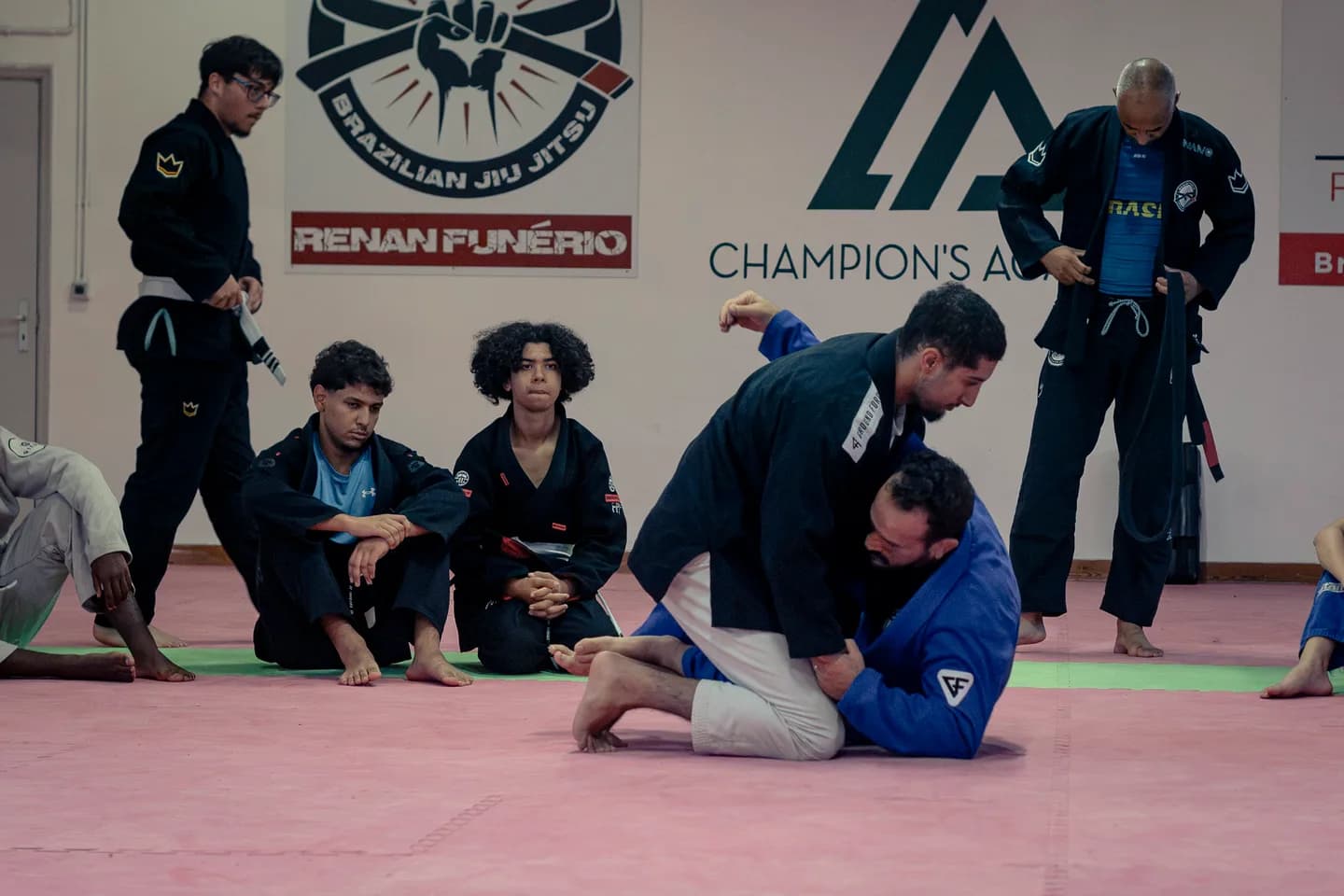 Démonstration d’une technique de jiu-jitsu en kimono devant un groupe sur les tatamis du club